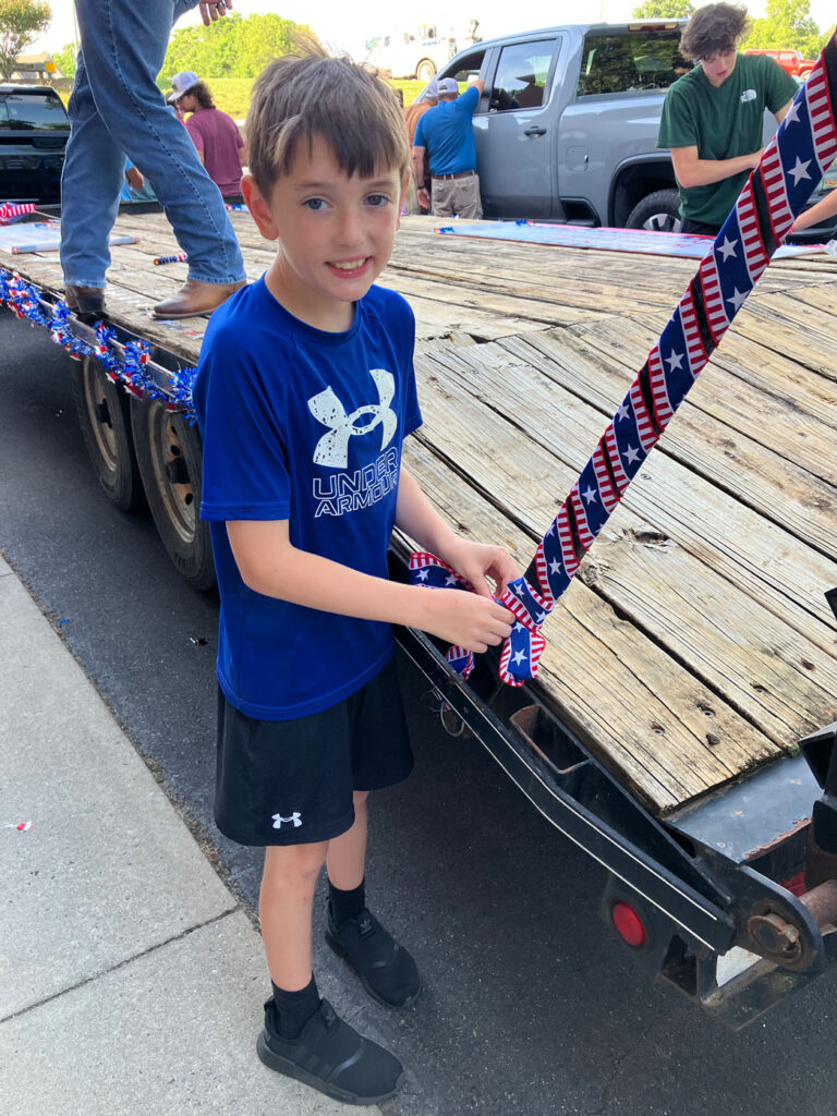 child standing beside parade float for church